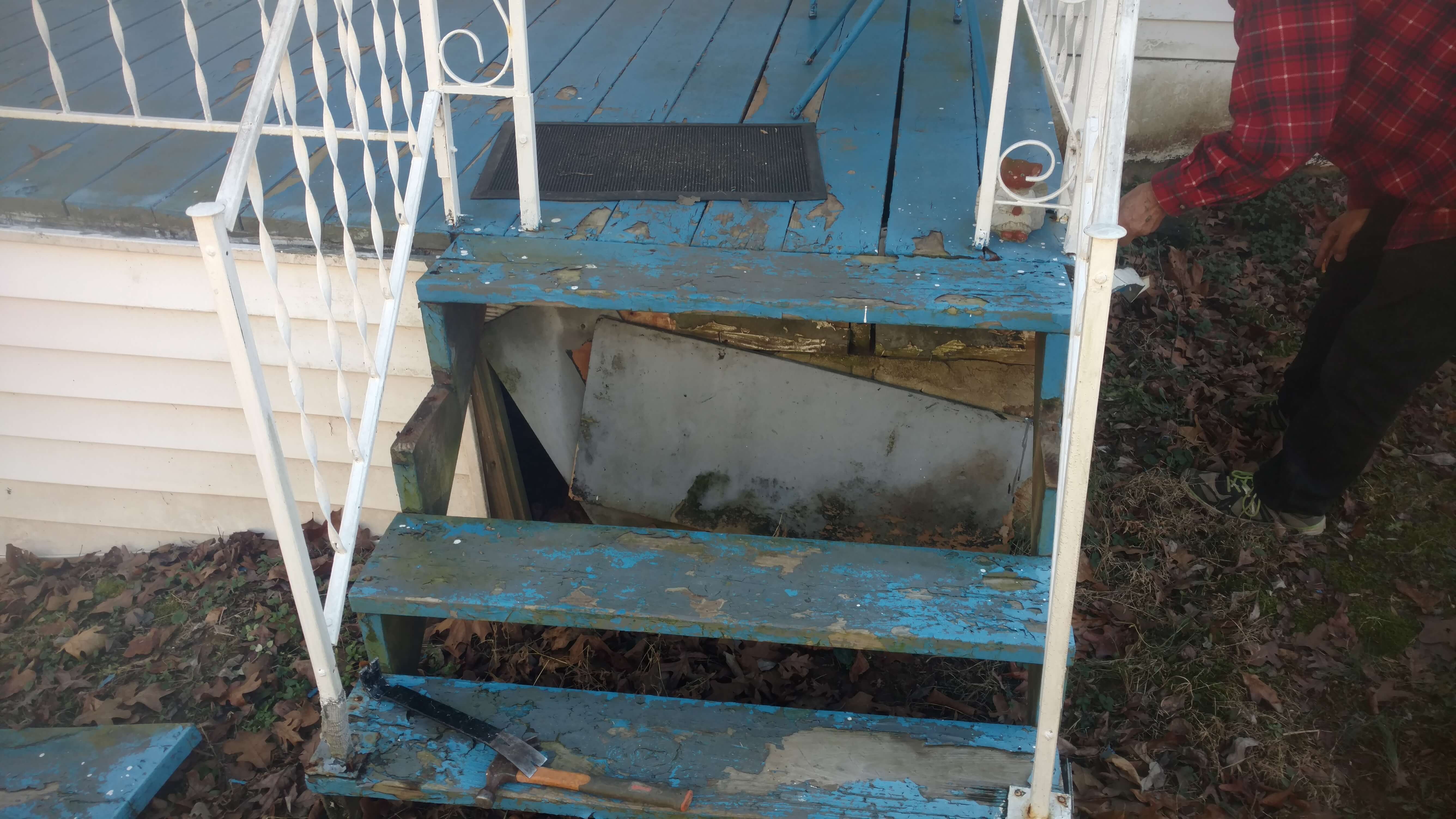 Worn and damaged stairs and a small porch
